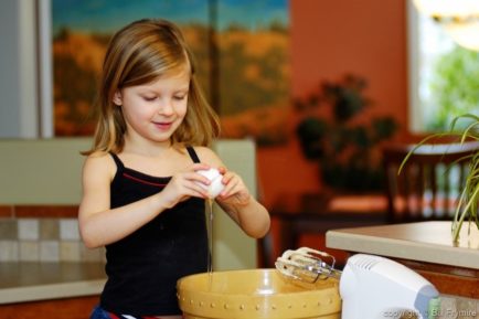 young girl cracking an egg - making cookies